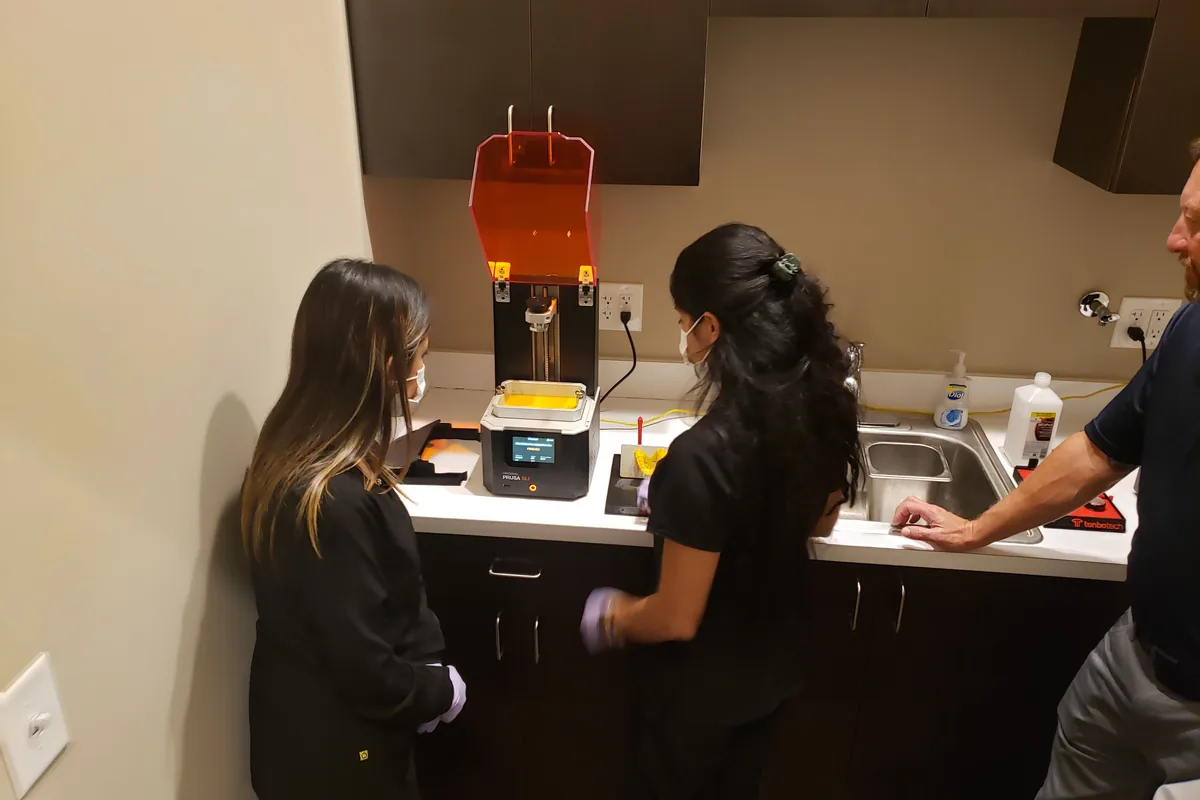 Two staff members being trained on a newly installed resin printer at a client site