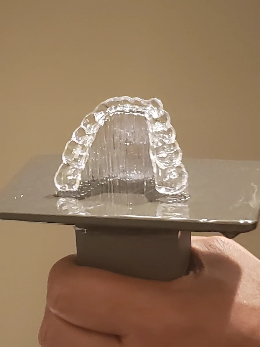 Clear resin print on a build plate held in a hand